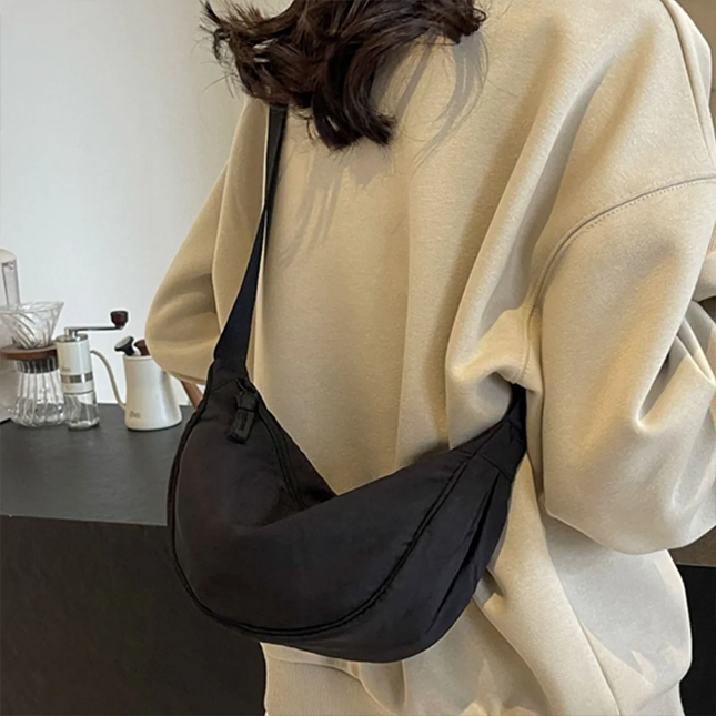 Half moon crossbody sling bag in black worn across the body