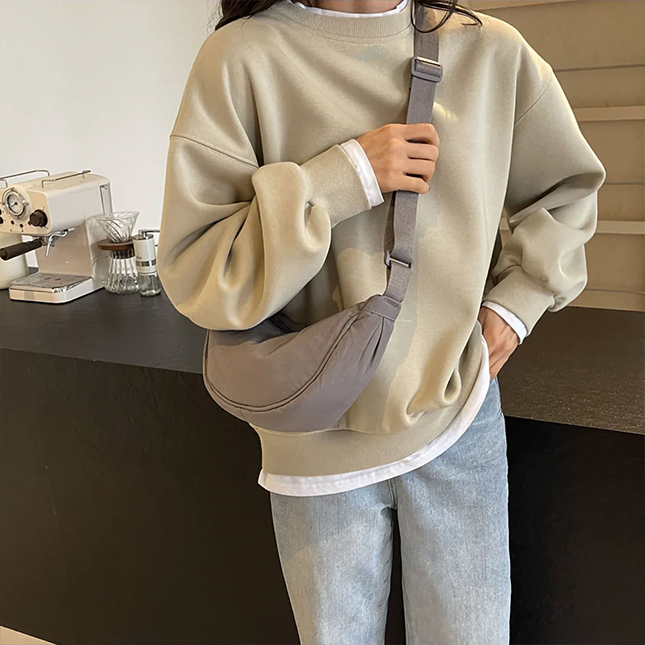 Half moon crossbody sling bag in grey worn across the body