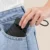 19 inch compact uv umbrella in black folded, fitting into a jeans pocket
