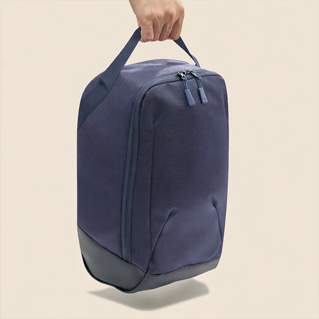 Solaris atlas shoe bag in navy held up by the handle, side view
