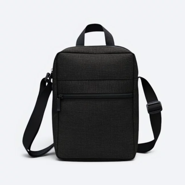 Kairos sling bag in black, front view with top handle and zip pocket