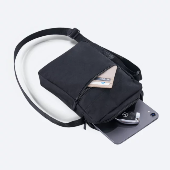 Kairos sling bag in black opened, showing card holder, car key and tablet inside